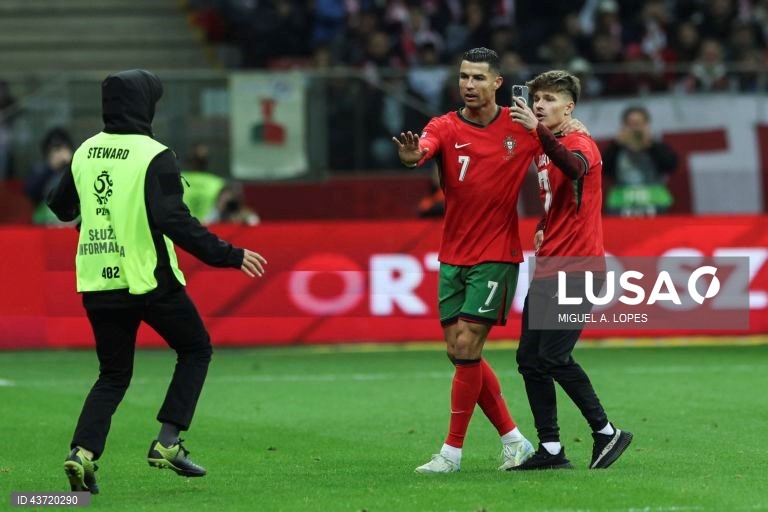 Um fã tenta tirar uma selfie com o jogador da seleção de Portugal Cristiano Ronaldo (C), após invadir o relvado, durante o jogo da Fase de Grupos - Grupo 1 - da Liga das Nações da UEFA, Polónia vs Portugal, no Estádio Narodowy, em Varsóvia, Polónia, 12 de outubro de 2024. MIGUEL A. LOPES/LUSA