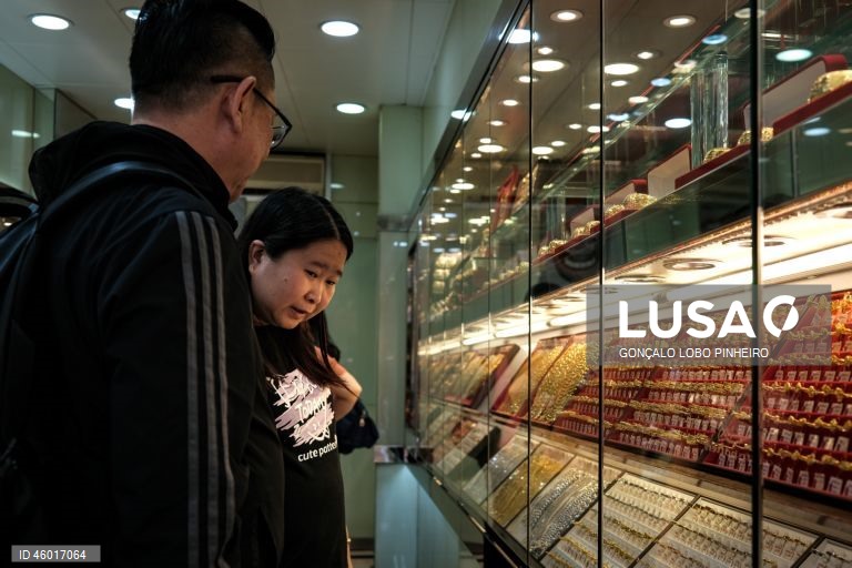 Populares observam uma montra de uma ourivesaria em Macau, China, 12 de novembro de 2025. A tradição da compra e oferta de ouro em Macau está a segurar a atividade das ourivesarias, que, não obstante os preços recorde do metal amarelo, mantêm o volume de transações, ainda que com menos peso total transacionado. (ACOMPANHA TEXTO DA LUSA DO DIA 16 DE NOVEMBRO DE 2025). GONÇALO LOBO PINHEIRO/LUSA