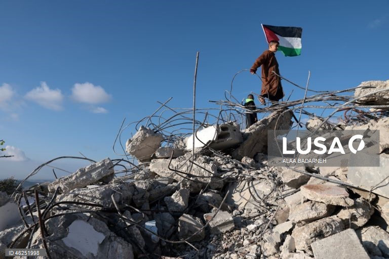 Um menino palestiniano agita uma bandeira palestiniana sobre os escombros da casa pertencente à família de Malik Ismail Salem na aldeia de Bizarya, perto da cidade de Nablus, na Cisjordânia. O exército israelita demoliu a casa de Malik Ismail Salem, que foi morto por tiros israelitas em 10 de julho de 2025, de acordo com a agência de notícias palestiniana WAFA.