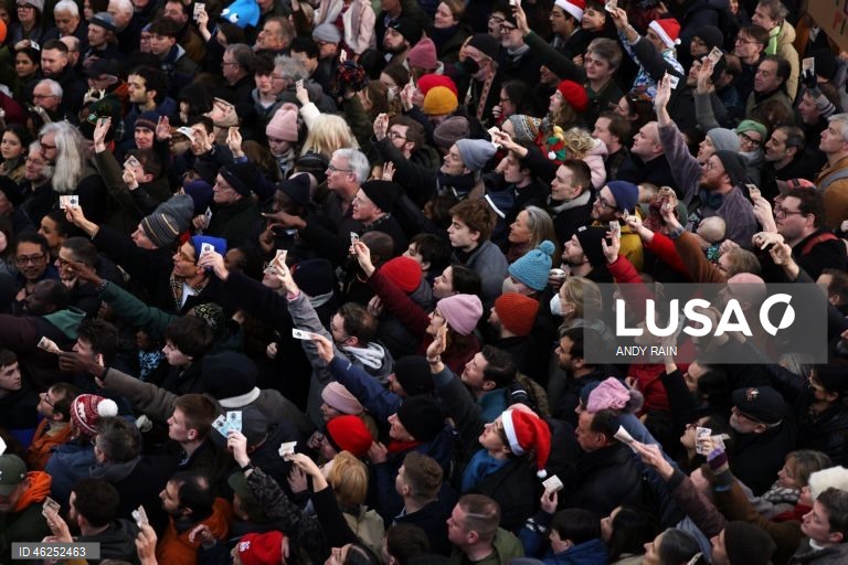 Pessoas observam enquanto talhantes distribuem carne no leilão de carne de Natal em Smithfield, Londres, Grã-Bretanha. Centenas de pessoas reunem-se para ter a oportunidade de comprar carne a preços promocionais na véspera de Natal no mercado de Smithfield, em Londres.