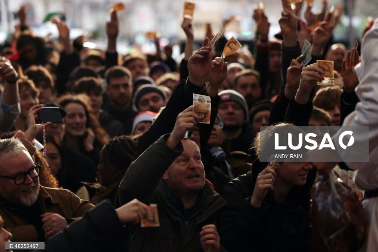 Pessoas observam enquanto talhantes distribuem carne no leilão de carne de Natal em Smithfield, Londres, Grã-Bretanha. Centenas de pessoas reunem-se para ter a oportunidade de comprar carne a preços promocionais na véspera de Natal no mercado de Smithfield, em Londres.