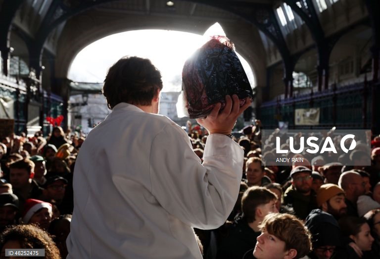 Pessoas observam enquanto talhantes distribuem carne no leilão de carne de Natal em Smithfield, Londres, Grã-Bretanha. Centenas de pessoas reunem-se para ter a oportunidade de comprar carne a preços promocionais na véspera de Natal no mercado de Smithfield, em Londres.