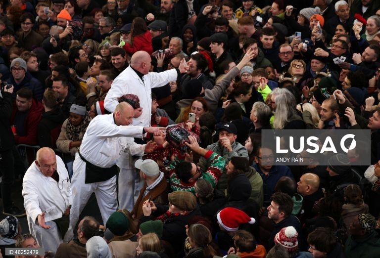 Pessoas observam enquanto talhantes distribuem carne no leilão de carne de Natal em Smithfield, Londres, Grã-Bretanha. Centenas de pessoas reunem-se para ter a oportunidade de comprar carne a preços promocionais na véspera de Natal no mercado de Smithfield, em Londres.