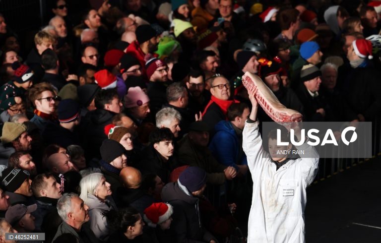 Pessoas observam enquanto talhantes distribuem carne no leilão de carne de Natal em Smithfield, Londres, Grã-Bretanha. Centenas de pessoas reunem-se para ter a oportunidade de comprar carne a preços promocionais na véspera de Natal no mercado de Smithfield, em Londres.