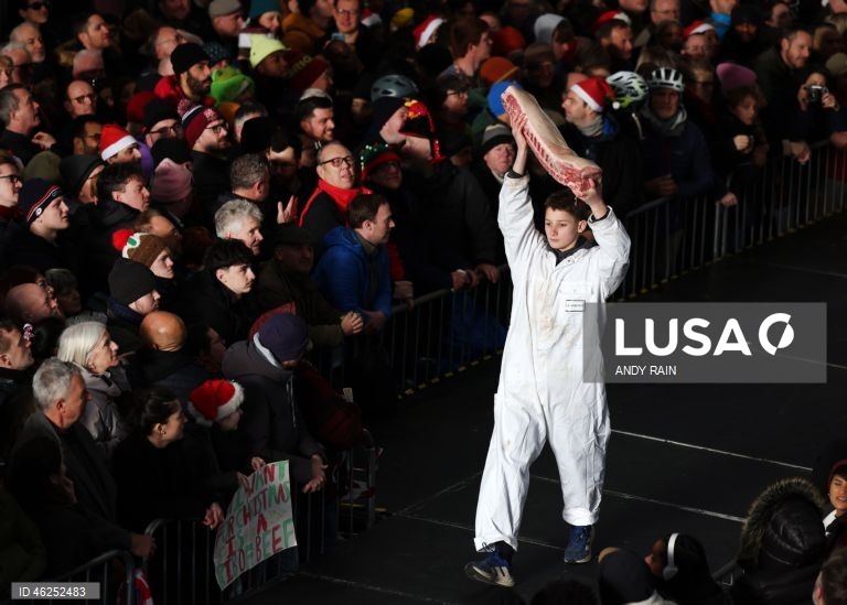 Pessoas observam enquanto talhantes distribuem carne no leilão de carne de Natal em Smithfield, Londres, Grã-Bretanha. Centenas de pessoas reunem-se para ter a oportunidade de comprar carne a preços promocionais na véspera de Natal no mercado de Smithfield, em Londres.