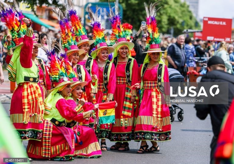 Pessoas vestem trajes tradicionais enquanto participam no Carnaval das Culturas em Berlim, Alemanha. O desfile envolve mais de 4 000 participantes que exibem as culturas dos seus países de origem. O Carnaval das Culturas é celebrado anualmente em Berlim desde 1996 e pretende ser um símbolo da diversidade e da coexistência pacífica. 