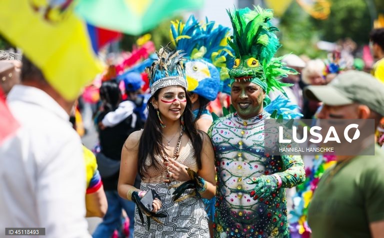 Pessoas vestem trajes tradicionais enquanto participam no Carnaval das Culturas em Berlim, Alemanha. O desfile envolve mais de 4 000 participantes que exibem as culturas dos seus países de origem. O Carnaval das Culturas é celebrado anualmente em Berlim desde 1996 e pretende ser um símbolo da diversidade e da coexistência pacífica. 