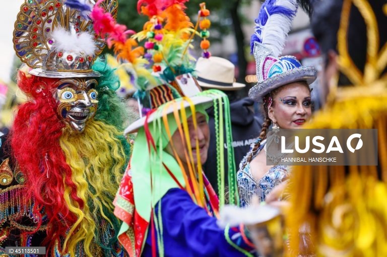 Pessoas vestem trajes tradicionais enquanto participam no Carnaval das Culturas em Berlim, Alemanha. O desfile envolve mais de 4 000 participantes que exibem as culturas dos seus países de origem. O Carnaval das Culturas é celebrado anualmente em Berlim desde 1996 e pretende ser um símbolo da diversidade e da coexistência pacífica. 
