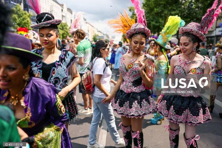 Pessoas vestem trajes tradicionais enquanto participam no Carnaval das Culturas em Berlim, Alemanha. O desfile envolve mais de 4 000 participantes que exibem as culturas dos seus países de origem. O Carnaval das Culturas é celebrado anualmente em Berlim desde 1996 e pretende ser um símbolo da diversidade e da coexistência pacífica. 