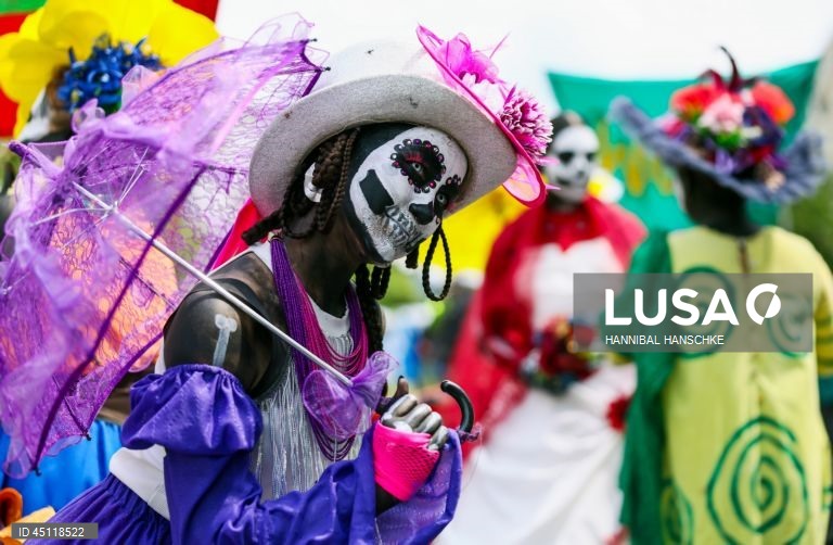 Pessoas vestem trajes tradicionais enquanto participam no Carnaval das Culturas em Berlim, Alemanha. O desfile envolve mais de 4 000 participantes que exibem as culturas dos seus países de origem. O Carnaval das Culturas é celebrado anualmente em Berlim desde 1996 e pretende ser um símbolo da diversidade e da coexistência pacífica. 