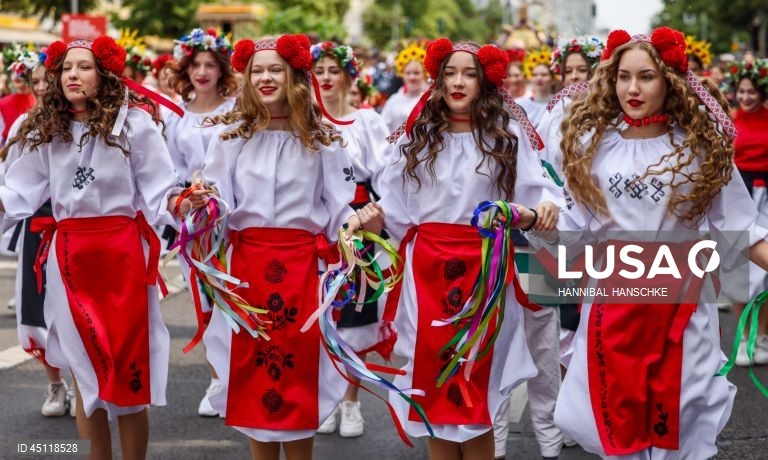 Pessoas vestem trajes tradicionais enquanto participam no Carnaval das Culturas em Berlim, Alemanha. O desfile envolve mais de 4 000 participantes que exibem as culturas dos seus países de origem. O Carnaval das Culturas é celebrado anualmente em Berlim desde 1996 e pretende ser um símbolo da diversidade e da coexistência pacífica. 