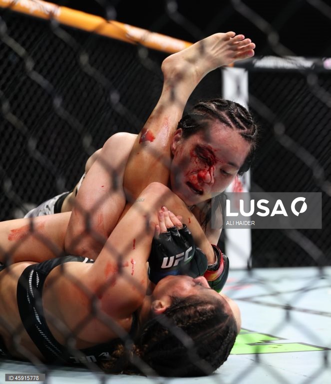 Jaqueline Amorim (vermelho) do Brasil e Mizuki Inoue (azul) do Japão em ação durante o UFC 321 na categoria peso palha feminino, em Abu Dhabi, Emirados Árabes Unidos.