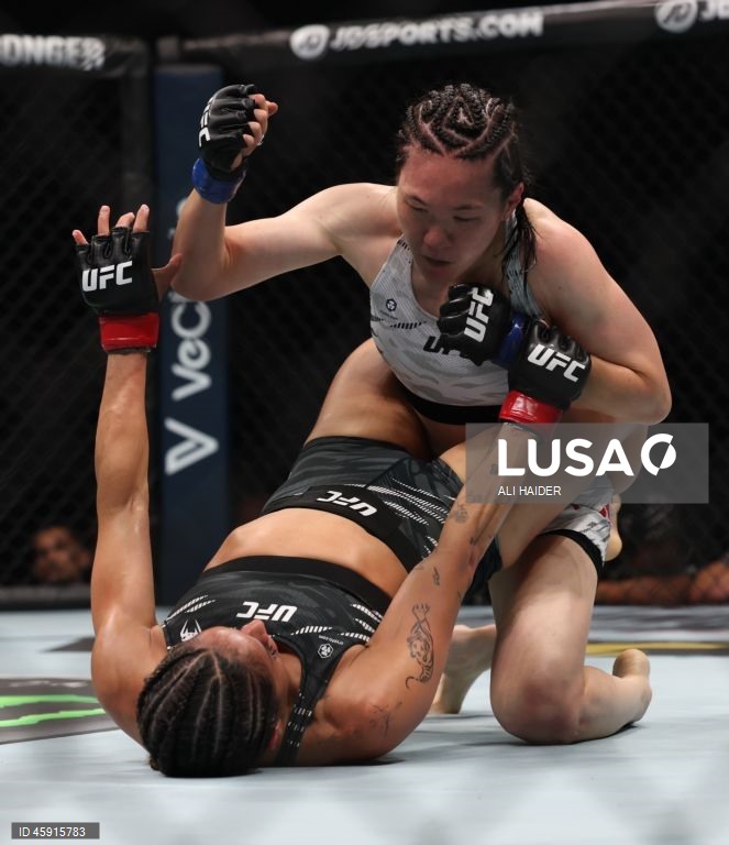 Jaqueline Amorim (vermelho) do Brasil e Mizuki Inoue (azul) do Japão em ação durante o UFC 321 na categoria peso palha feminino, em Abu Dhabi, Emirados Árabes Unidos.