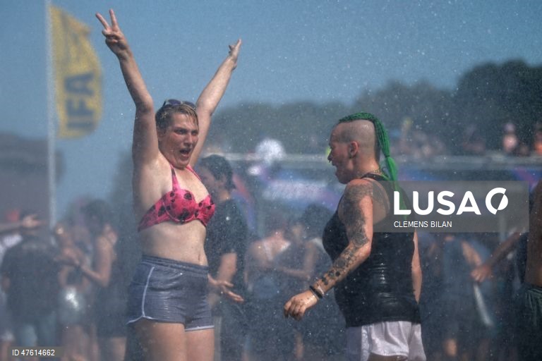 As pessoas refrescam-se com o jato de água de um canhão da polícia em frente à Coluna da Vitória, durante o desfile techno «Rave the Planet» em Berlim, Alemanha. O 5.º desfile techno «Rave the Planet» decorre sob o lema «Imagine Love».  